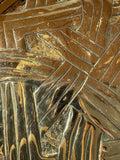 Close-up of interwoven strands in a repoussé Celtic knot, showing chased lines and light surface wear