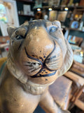 Close-up of the ceramic tiger planter face from a slightly elevated angle showing hand-painted eyes, brow detail, muzzle, whiskers, and the matte grey-brown glaze with light surface wear and minor paint loss.