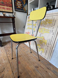 Side view of single yellow Formica dining chair with chrome legs and black trim.