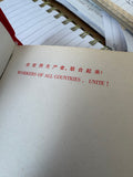 Open page of "Little Red Book" showing "Workers of All Countries, Unite!" printed in Chinese and English.
