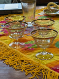 Set of four vintage 1950s cocktail glasses with gold trim on bright fabric