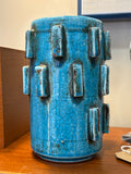 Front of a 17cm turquoise crackle glaze vase with staggered rows of raised blocks edged in dark brown