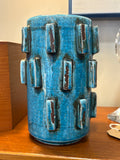 Side view of a sculptural turquoise vase with raised blocks and brown wipe glaze in Scandinavian style