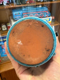Unglazed terracotta base of a turquoise crackle glaze vase, with turquoise glaze around the foot rim